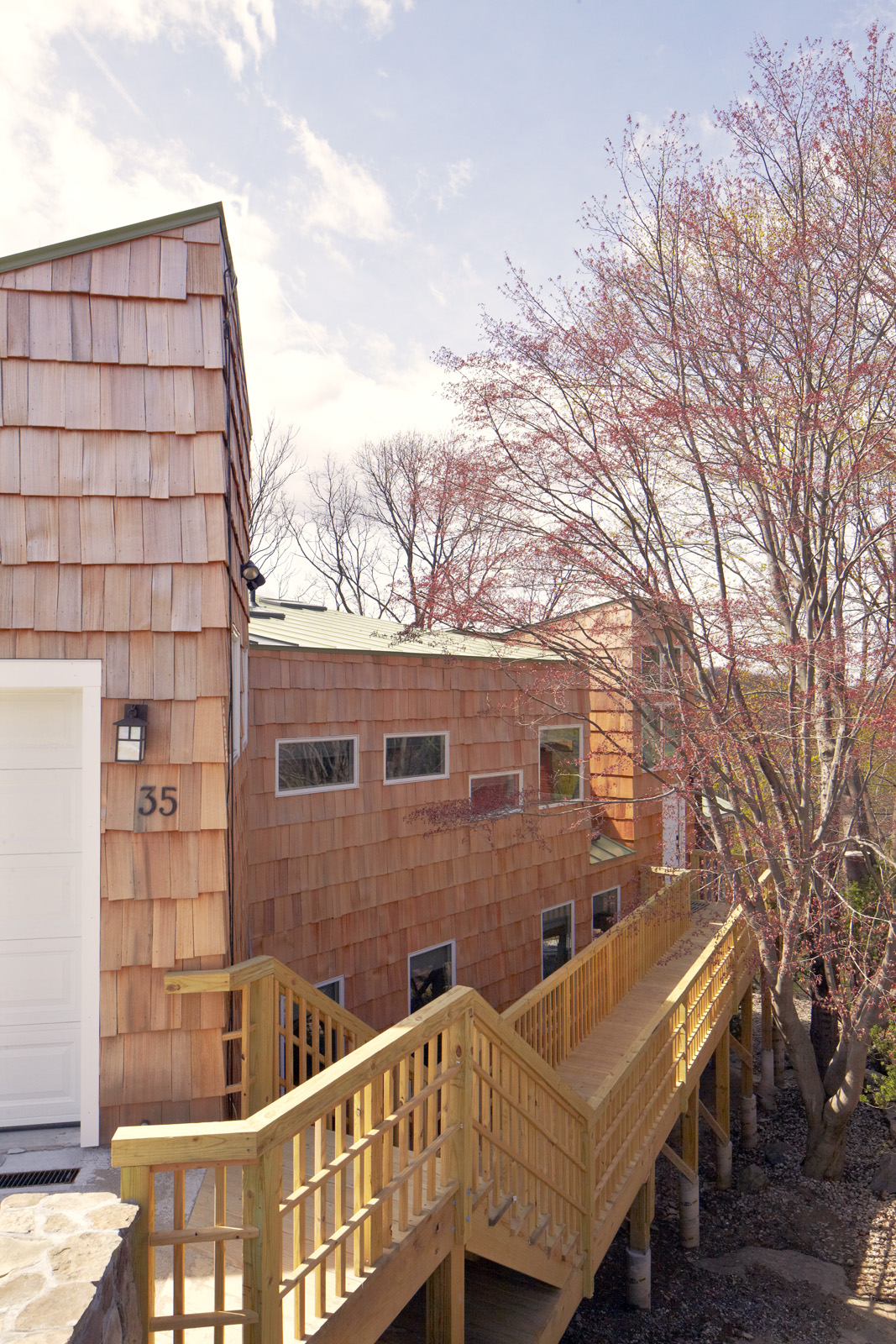 A bridge off the new garage creates a formal procession along the wooded site to