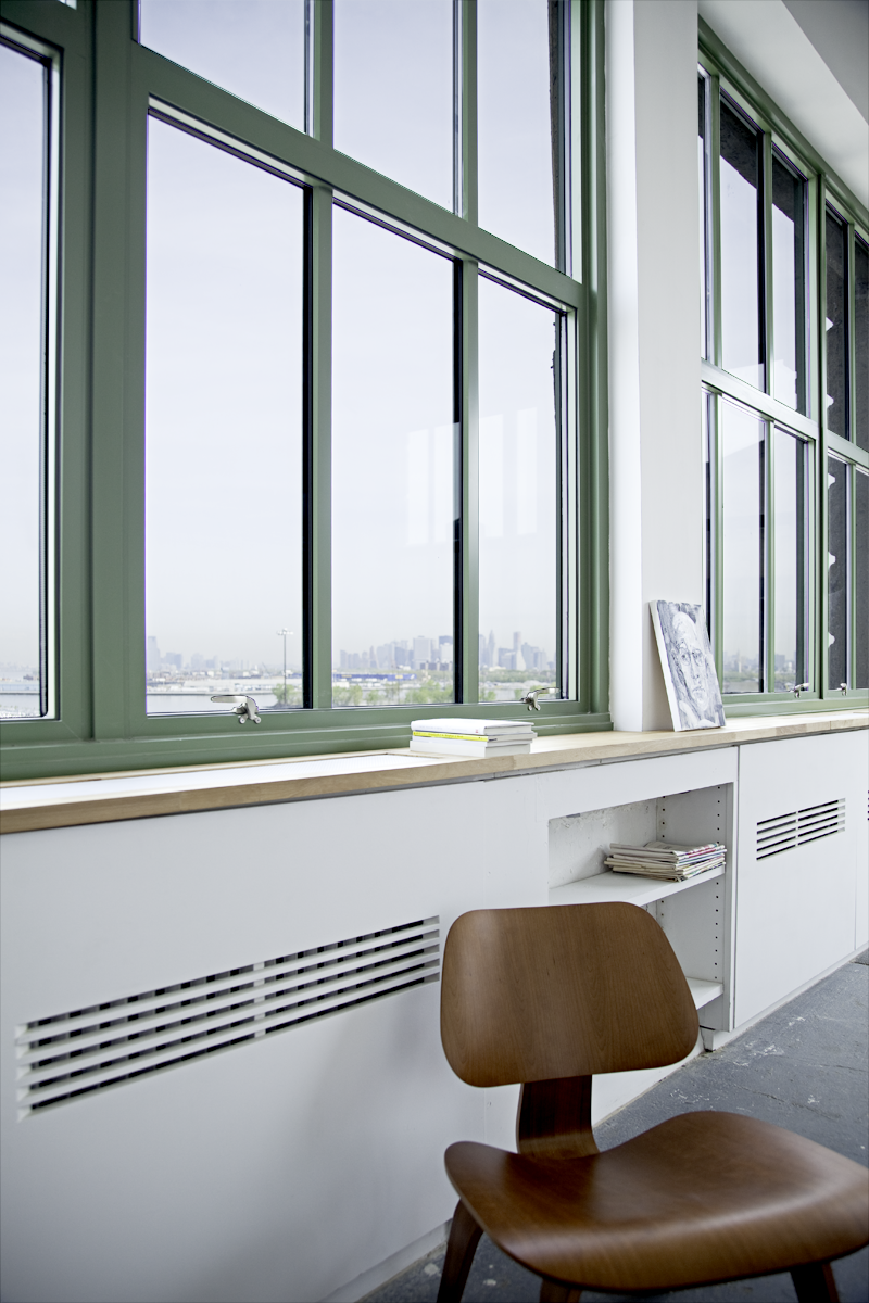 An integrated shelf below the wall of windows hides the radiators running the le